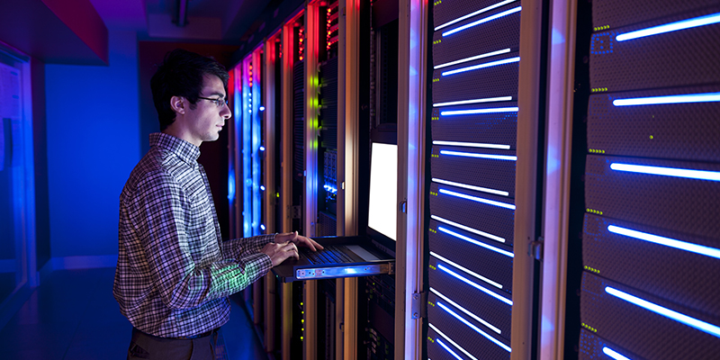 man working with a keyboard and monitor in a data center