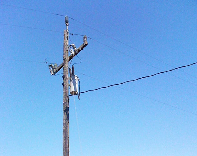 Installed Fault Tamer Fuse Limiter on a wooden pole conventional fuse cutout and a backup current-limiting fuse,